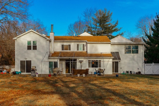 back of property with a gate, a yard, a chimney, and fence