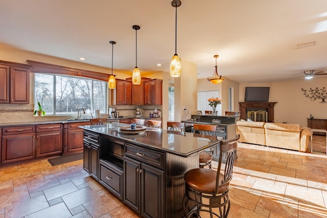 kitchen featuring dark countertops, tasteful backsplash, a sink, and stone tile flooring