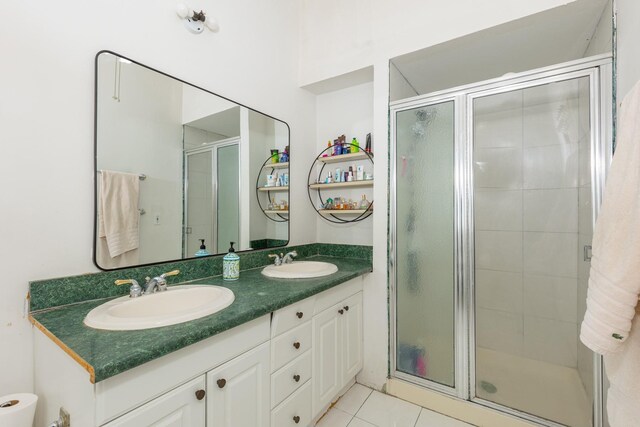 bathroom featuring double vanity, a stall shower, a sink, and tile patterned floors