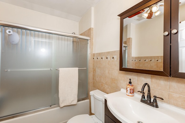 full bathroom featuring shower / bath combination with glass door, tile walls, visible vents, toilet, and vanity