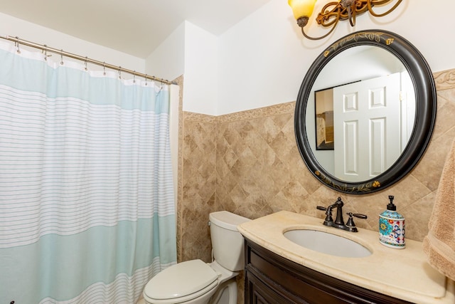 bathroom with toilet, curtained shower, vanity, and tile walls