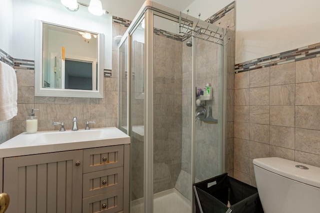 full bathroom with a stall shower, tile walls, and vanity