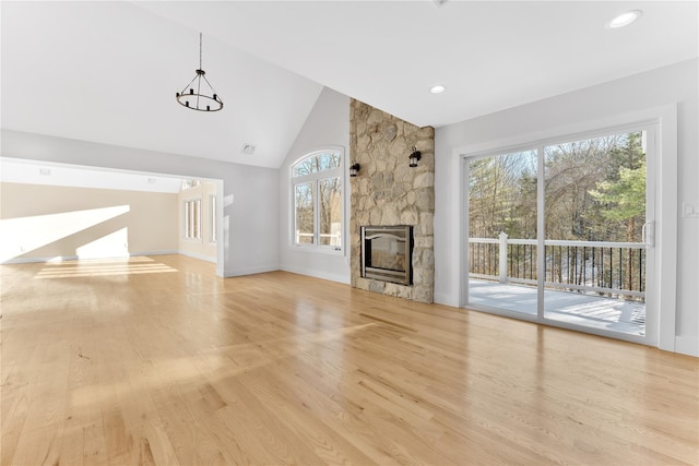 unfurnished living room with high vaulted ceiling, a fireplace, and light hardwood / wood-style floors