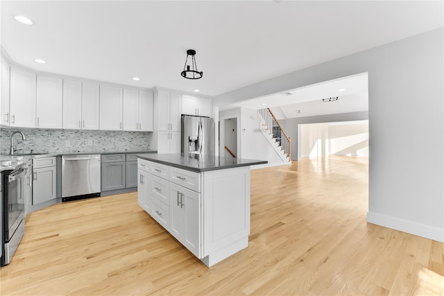 kitchen with a kitchen island, white cabinetry, appliances with stainless steel finishes, and pendant lighting