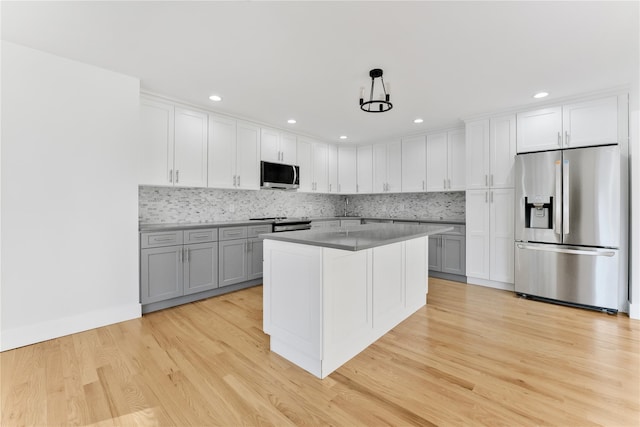 kitchen with stainless steel appliances, hanging light fixtures, gray cabinetry, and light wood-type flooring