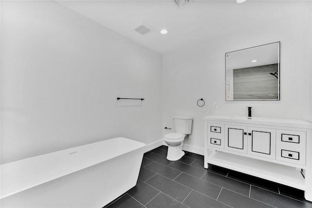 bathroom featuring vanity, a tub to relax in, tile patterned floors, and toilet