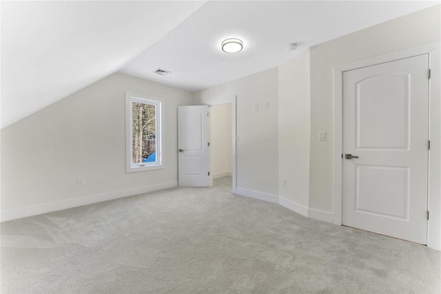 bonus room with light colored carpet and vaulted ceiling