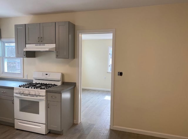 kitchen featuring hardwood / wood-style floors, white range with gas cooktop, and gray cabinetry