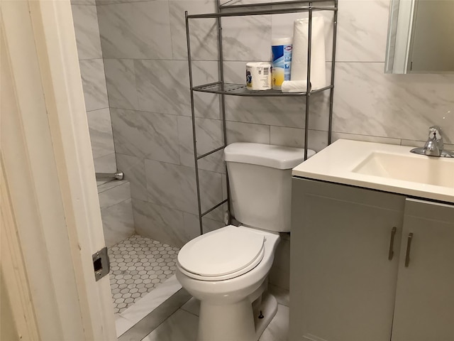 bathroom with tile walls, backsplash, a tile shower, vanity, and toilet