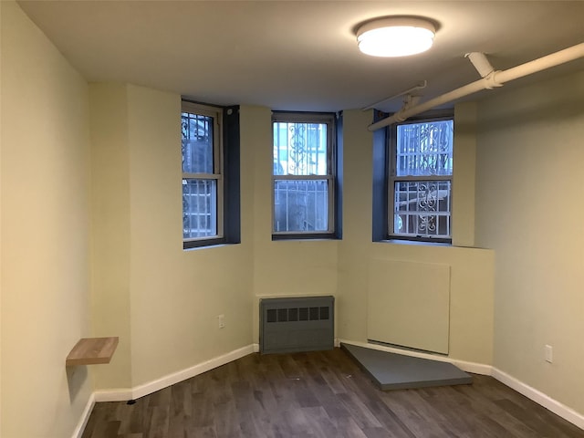 spare room with dark wood-type flooring and radiator