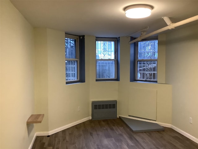 unfurnished room featuring dark wood-type flooring and radiator heating unit