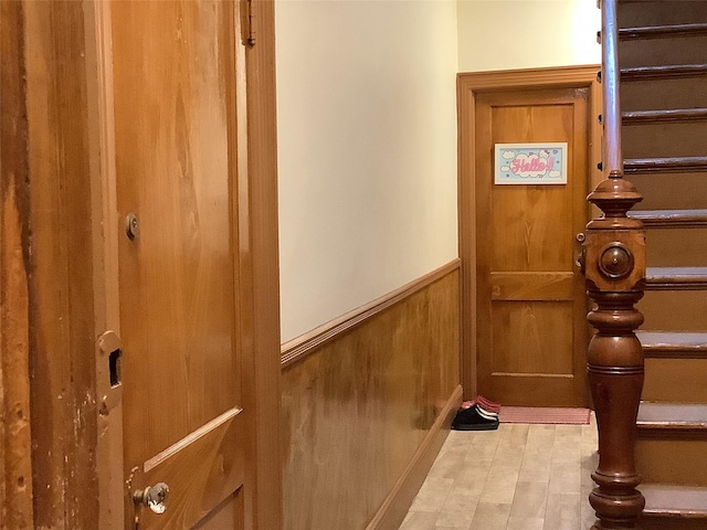 doorway with light wood-type flooring and wood walls