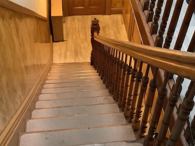 stairs featuring wood-type flooring and wooden walls