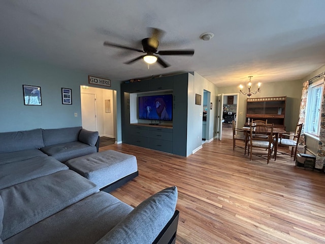 living room featuring ceiling fan with notable chandelier and light hardwood / wood-style flooring