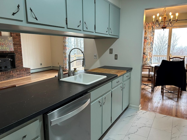 kitchen with a chandelier, a fireplace, dishwasher, and sink