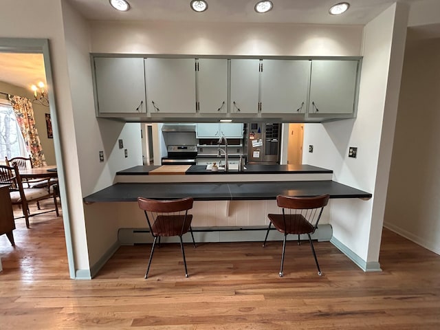 kitchen with sink, light hardwood / wood-style flooring, stainless steel appliances, and kitchen peninsula