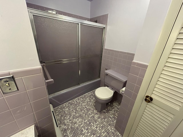 bathroom featuring tile patterned flooring, toilet, and tile walls