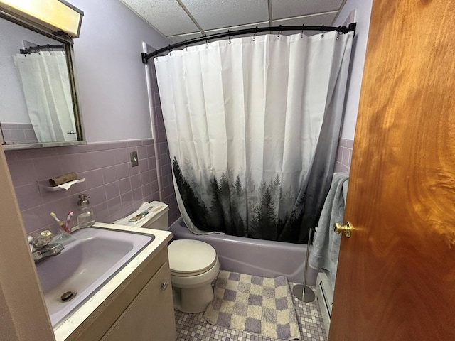 full bathroom with tile walls, vanity, a baseboard heating unit, toilet, and shower / bath combo