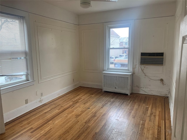 unfurnished room with cooling unit, radiator heating unit, ceiling fan, and light hardwood / wood-style flooring