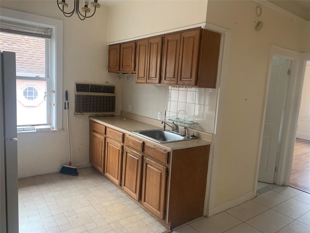 kitchen featuring sink, a chandelier, refrigerator, and decorative backsplash