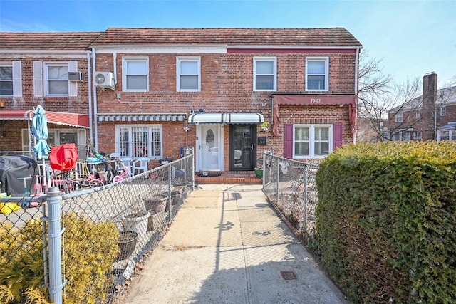 view of property featuring fence private yard, an AC wall unit, and brick siding