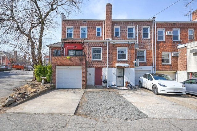 view of front of house featuring a garage, concrete driveway, brick siding, and a chimney