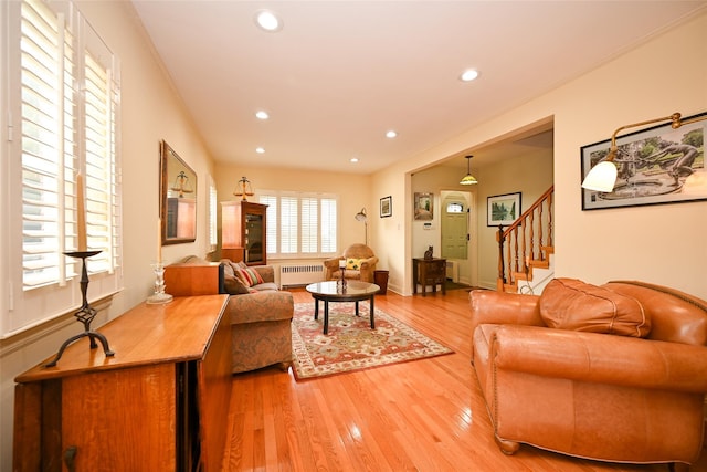 living room featuring recessed lighting, radiator, light wood-style flooring, stairway, and ornamental molding