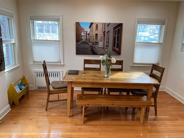 dining room with radiator heating unit, light wood-type flooring, and baseboards