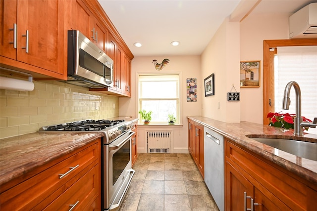 kitchen featuring decorative backsplash, radiator, a wall unit AC, appliances with stainless steel finishes, and a sink