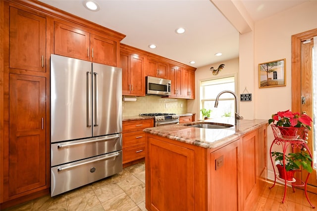 kitchen featuring light stone counters, brown cabinets, stainless steel appliances, tasteful backsplash, and a sink