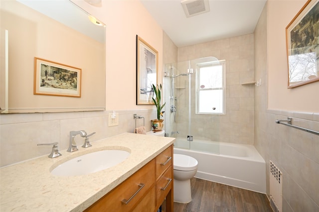 full bath with toilet, visible vents, tile walls, and wood finished floors