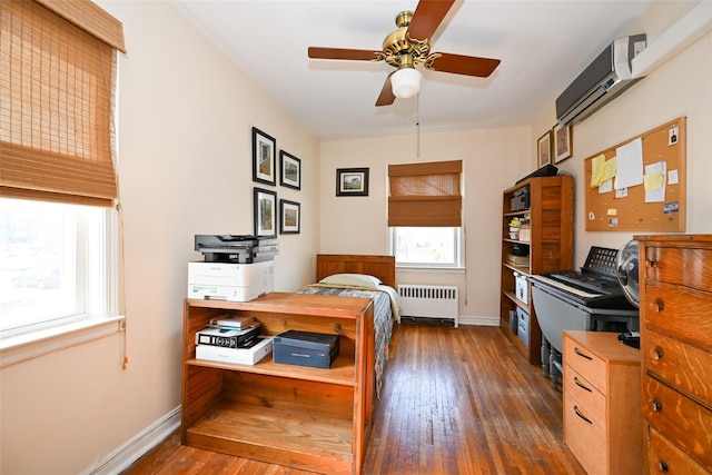 bedroom with baseboards, a ceiling fan, radiator heating unit, wood-type flooring, and a wall mounted AC