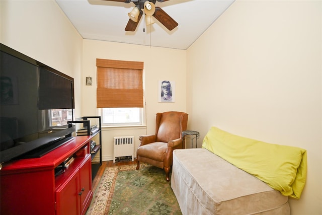 living area featuring radiator, a ceiling fan, and dark wood-type flooring