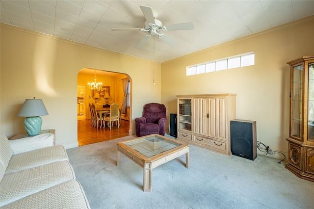 carpeted living room with ornamental molding and ceiling fan with notable chandelier