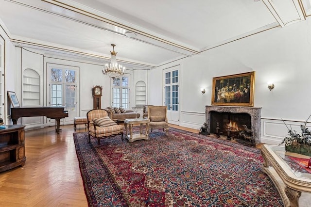 living area with parquet flooring, built in features, beamed ceiling, a notable chandelier, and a premium fireplace