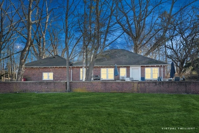 back of house featuring brick siding and a lawn