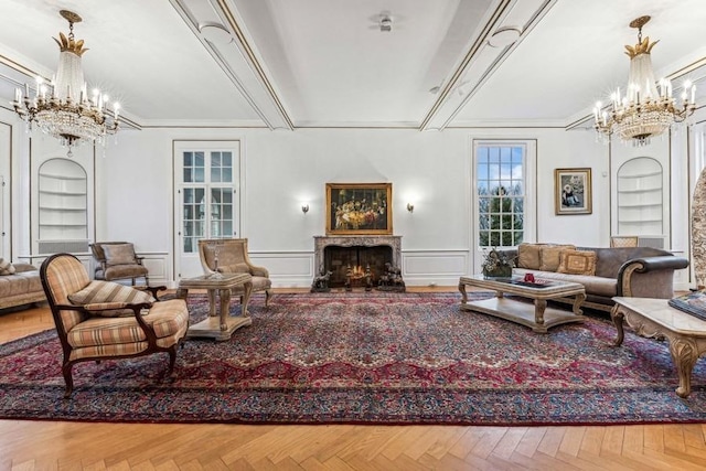 living room featuring built in features, a warm lit fireplace, a notable chandelier, and a decorative wall