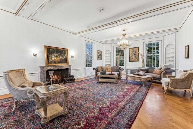 living room with a wainscoted wall, a decorative wall, a premium fireplace, ornamental molding, and a chandelier