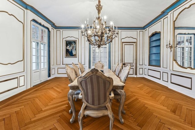 dining room with a notable chandelier, crown molding, and a decorative wall