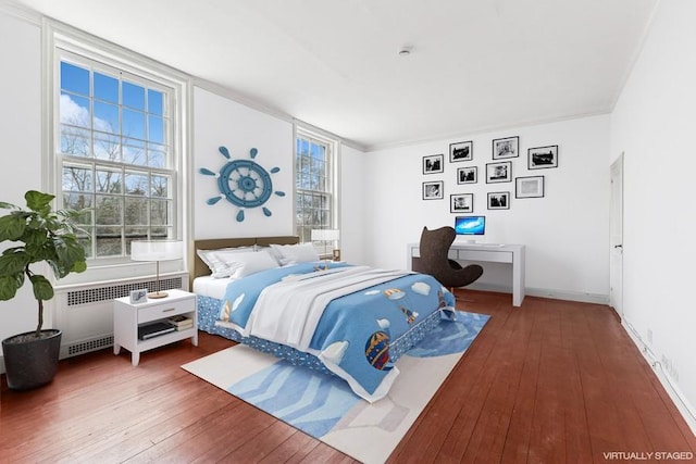 bedroom with baseboards, radiator heating unit, and hardwood / wood-style flooring