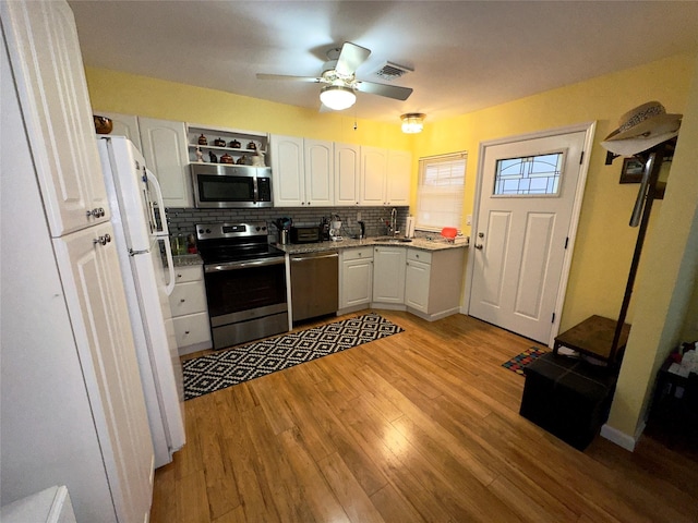 kitchen with sink, white cabinetry, stainless steel appliances, light hardwood / wood-style floors, and decorative backsplash