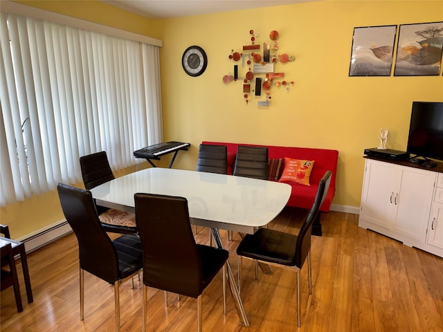 dining space with a baseboard heating unit and light hardwood / wood-style flooring