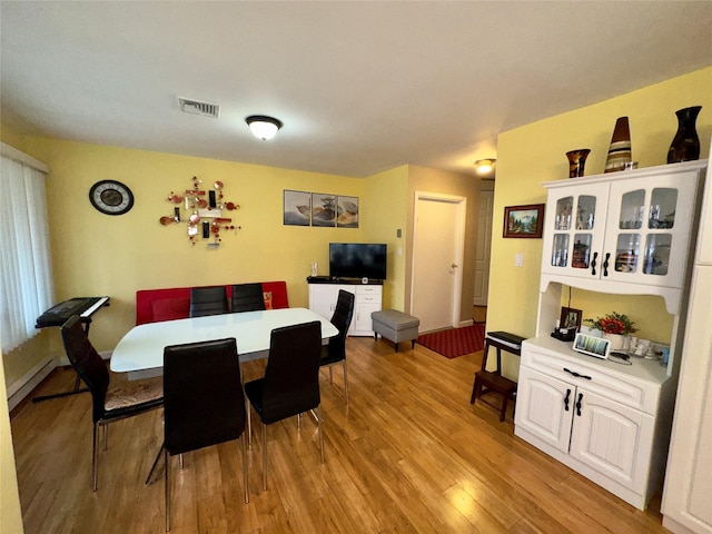 dining area with a baseboard heating unit and light hardwood / wood-style floors