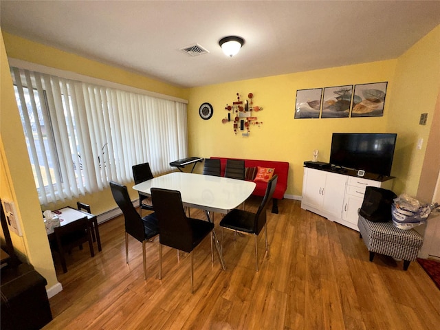 dining space with hardwood / wood-style flooring and a baseboard radiator