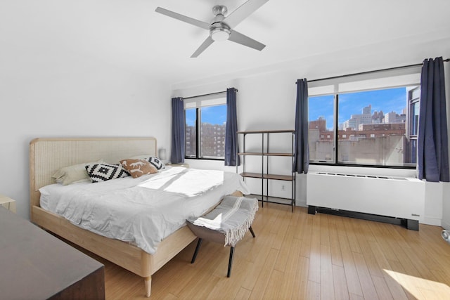 bedroom featuring radiator, ceiling fan, and light hardwood / wood-style flooring