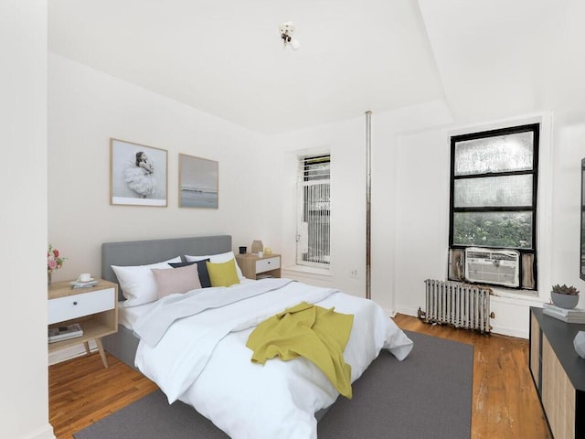 bedroom with radiator and dark hardwood / wood-style flooring