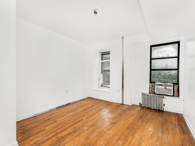 unfurnished room with cooling unit, radiator, and hardwood / wood-style flooring