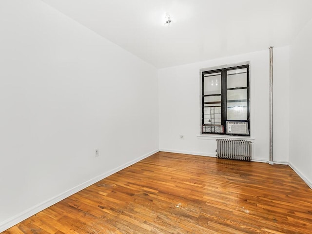 unfurnished room featuring hardwood / wood-style floors, radiator heating unit, and cooling unit