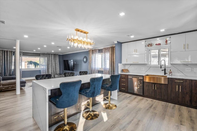 kitchen featuring a kitchen island, a breakfast bar, white cabinetry, dishwasher, and sink