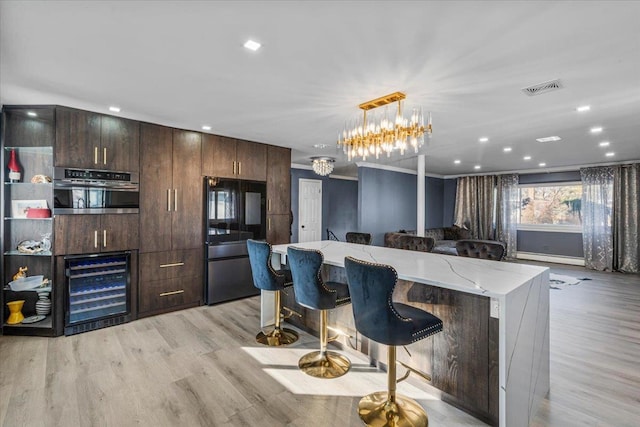 kitchen with a kitchen island, a breakfast bar area, wine cooler, oven, and hanging light fixtures